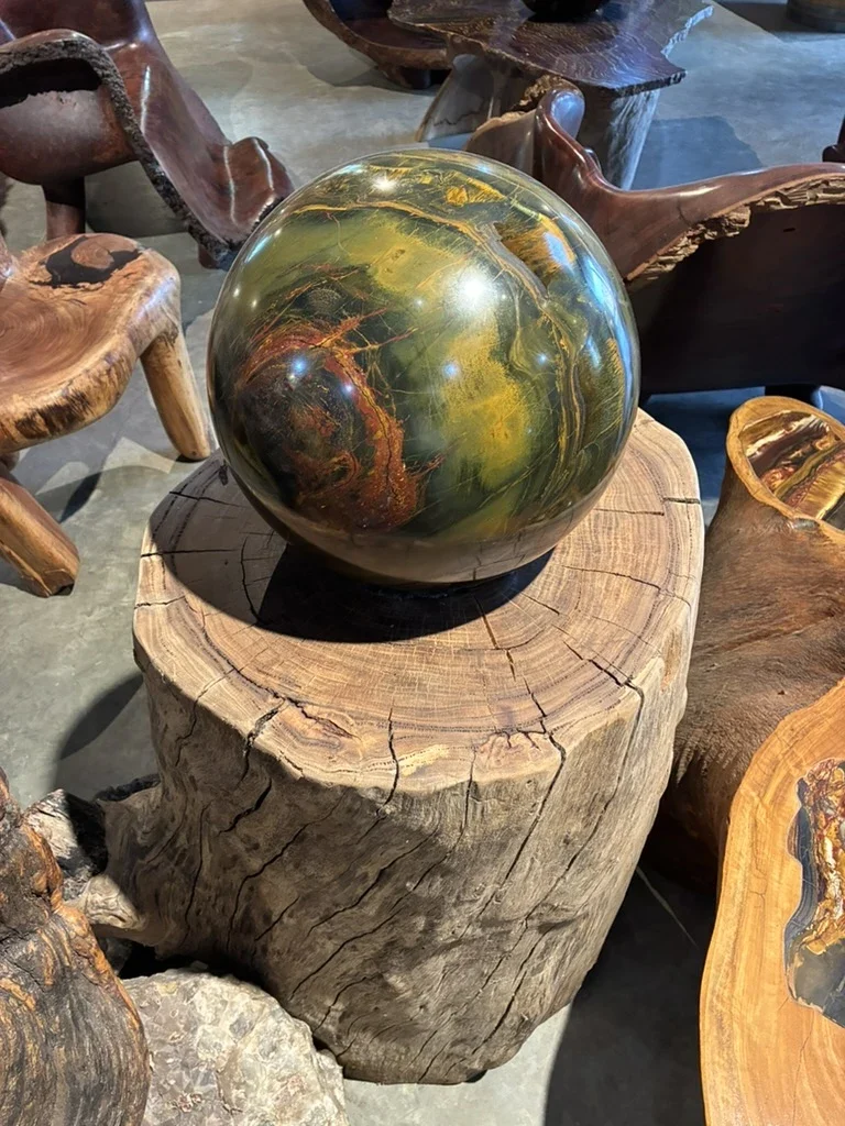 Complete polished mineral sphere resting on a natural timber plinth