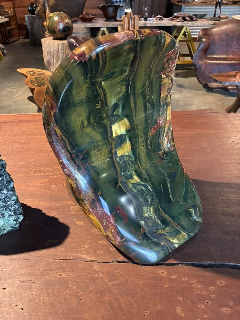Green and gold polished rock sculpture on a timber table
