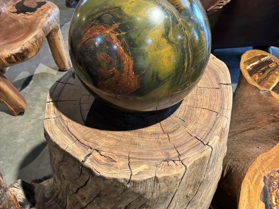 Large polished sphere resting on a natural timber plinth